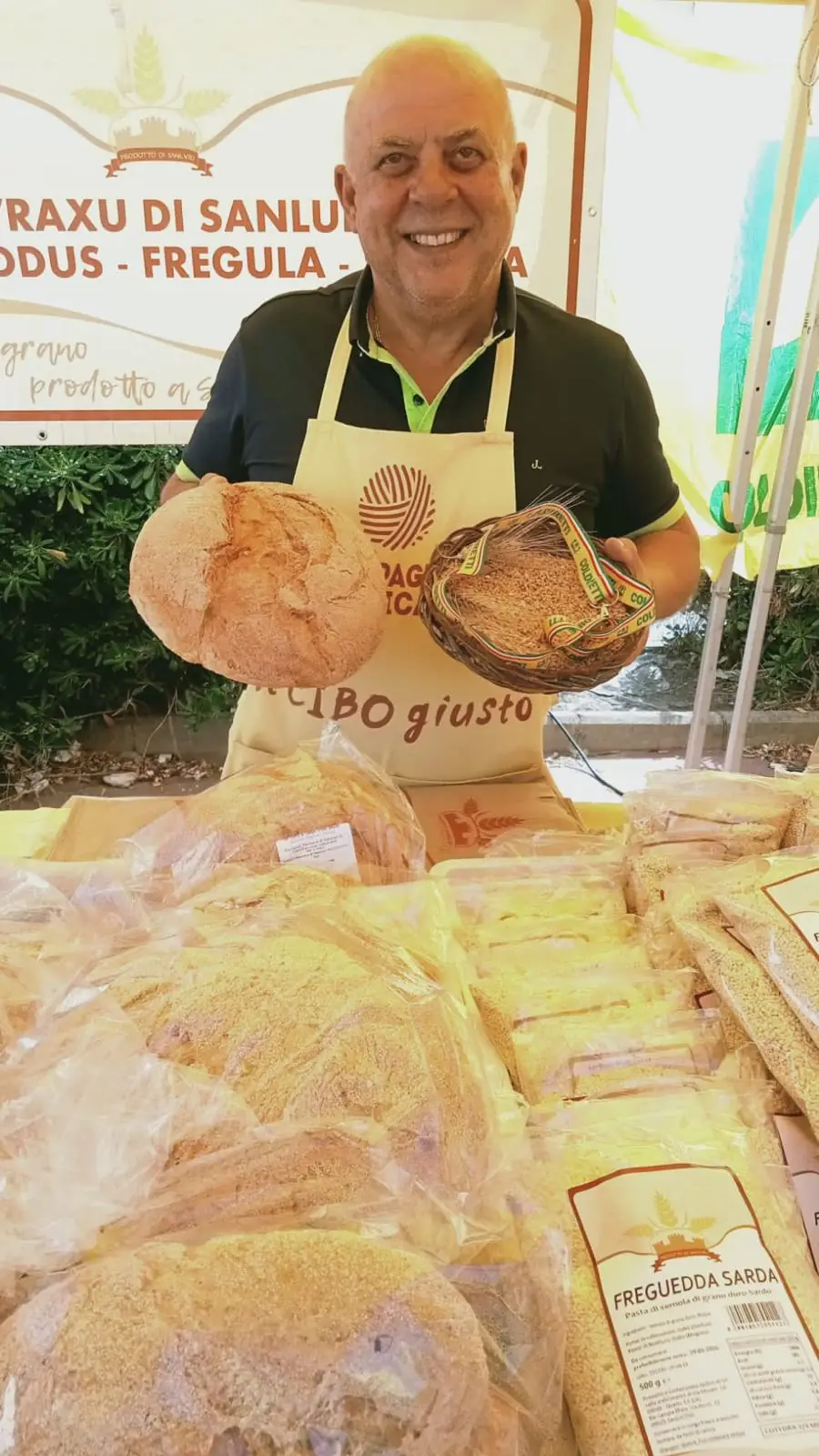 Un produttore di Prodotto di Sanluri al mercato con il pane appena sfornato